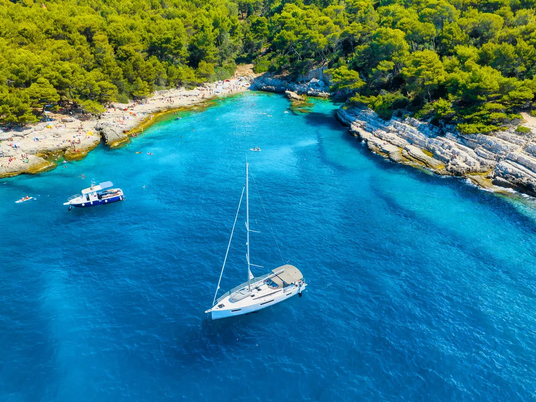Aerial view of a boat in a turquoise Adriatic bay