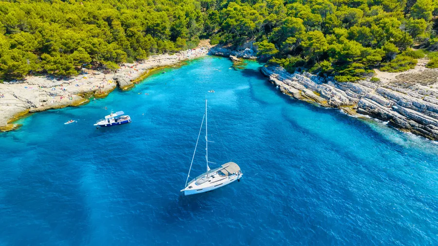 Aerial view of a boat in a turquoise Adriatic bay