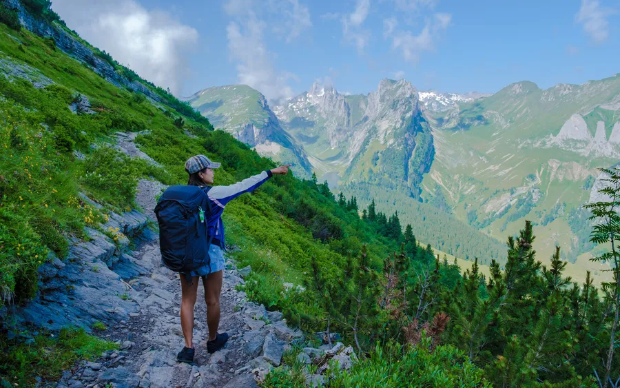 Hikers on a high alpine trail with glaciers behind