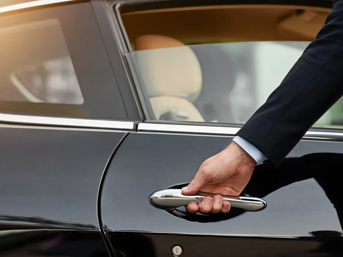 A chauffeur opening the door of a luxury car
