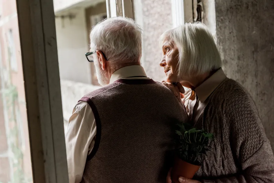 Senior couple looking out of a window together