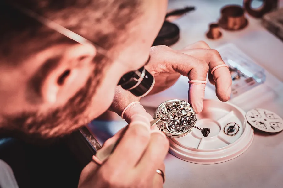 Watchmaker examining a mechanical watch movement with a loupe